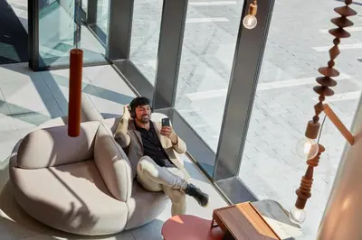 a man sitting in a chair looking at his cell phone at Adagio access Brussels Delta in Brussels