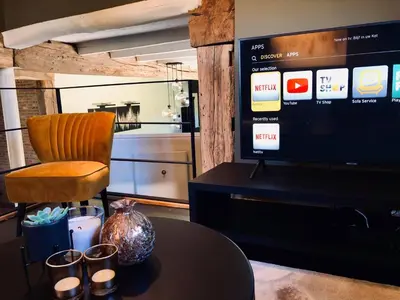 a room with a table and a chair and a television at 't Averhuys in Itegem