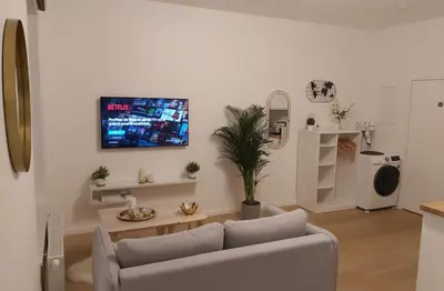 a living room with a couch and a tv on the wall at Logement luxueux dans le coeur de Bruxelles in Brussels