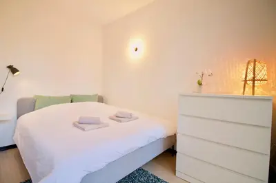 a small bedroom with a white bed and a dresser at Amazing & cosy studio perfect location 'Stephanie-Louise area' in Brussels