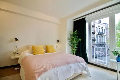 a bedroom with a bed and a large window at Splendid & cosy studio - perfect location 'Stephanie-Louise area' in Brussels