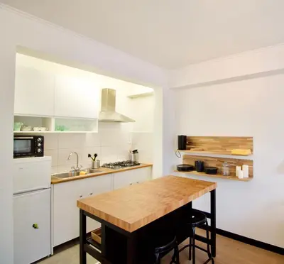 a kitchen with white cabinets and a wooden table at Splendid & cosy studio - perfect location 'Stephanie-Louise area' in Brussels
