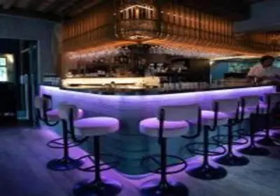 a bar with purple bar stools in a room at Nonam Boutique Hotel Gent in Ghent