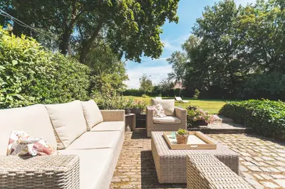 a patio with a white couch and chairs and a table at B&B Hof Ter Koningen in Aalst
