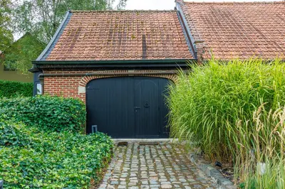 a garage with a blue door on a brick house at B&B Hof Ter Koningen in Aalst