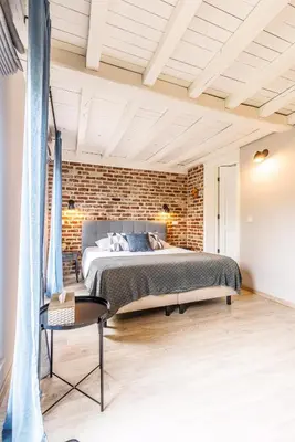 a bedroom with a bed and a brick wall at B&B Hof Ter Koningen in Aalst