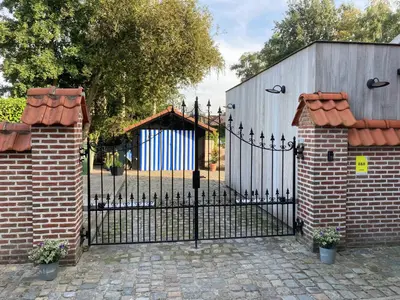 a black fence with a gate and a building at B&B Hof Ter Koningen in Aalst