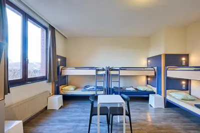 a room with three bunk beds and a table and chairs at HI Brussels Generation Europe Hostel in Brussels