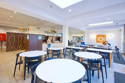 a cafeteria with white tables and chairs and people at HI Brussels Generation Europe Hostel in Brussels