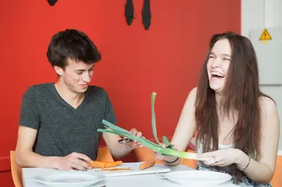 a man and a woman sitting at a table with vegetables at HI Brussels Jacques Brel Hostel in Brussels