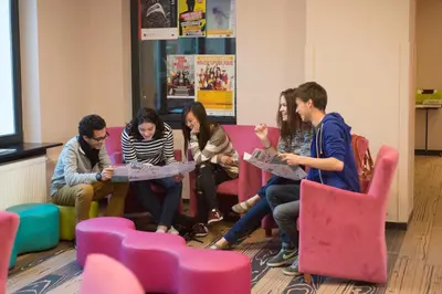 a group of people sitting around a table in a room at HI Brussels Jacques Brel Hostel in Brussels