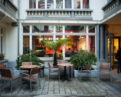 a patio with tables and chairs in front of a building at HI Brussels Jacques Brel Hostel in Brussels