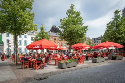 a group of people sitting at tables under red umbrellas at SHWAY - The Suit in Antwerp