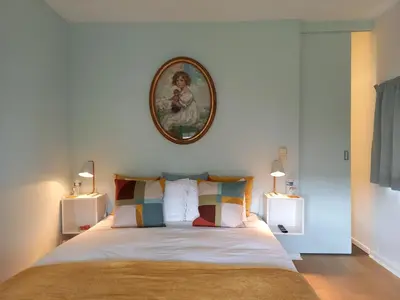 a bedroom with a bed with a picture on the wall at little cottage in Lasne