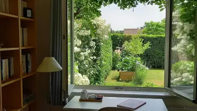a window with a view of a garden from a desk at little cottage in Lasne