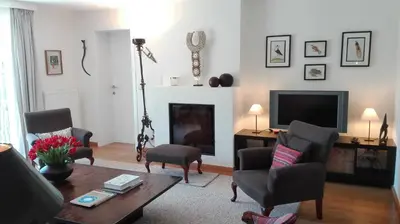 a living room with a table and chairs and a television at little cottage in Lasne