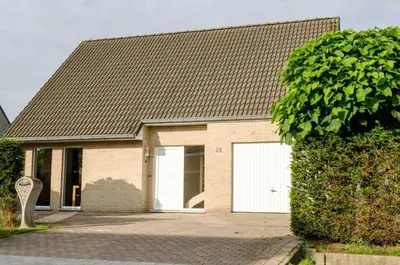 a brick house with two white garage doors at De Wilgoren in Kasterlee
