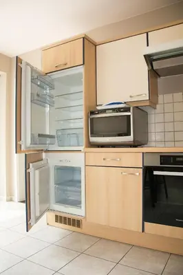 a kitchen with wooden cabinets and a microwave at De Wilgoren in Kasterlee