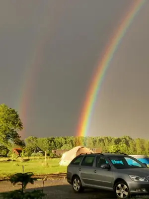 a car parked in a parking lot with a rainbow at Elingenhof in Elingen