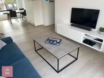 a living room with a blue couch and a table at Lovely & Stylish accommodations at P36 Gent, near the Center in Ghent