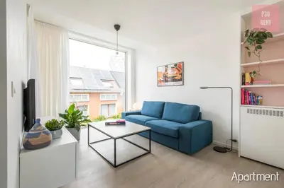 a living room with a blue couch and a table at Lovely & Stylish accommodations at P36 Gent, near the Center in Ghent