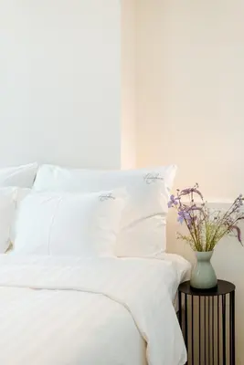 a bed with white sheets and a vase on a table at The Librarian by Domani Hotels in Ghent