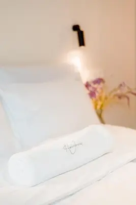 a white pillow on a bed with a cross on it at The Librarian by Domani Hotels in Ghent