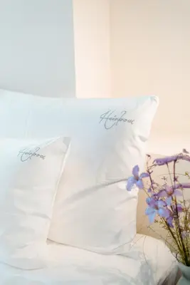 two white pillows sitting on a bed with flowers at The Librarian by Domani Hotels in Ghent