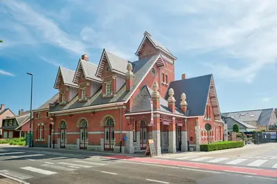 a large red brick building on the corner of a street at De Statie in Brecht