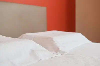 two beds with white sheets and a red wall at De Statie in Brecht