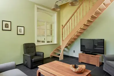 a living room with a tv and a staircase at De Statie in Brecht