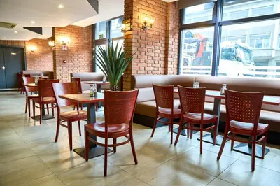 a restaurant with wooden tables and chairs and a brick wall at Hotel EUROPACITY in Brussels