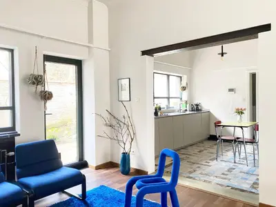 a living room with blue chairs and a kitchen at B&B Expo House in Antwerp