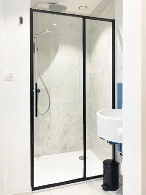 a glass shower door in a bathroom with a sink at B&B Expo House in Antwerp