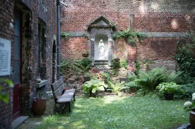 a garden with a bench and a statue in a brick building at Het Rustpunt in Ghent