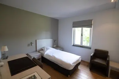 a bedroom with a bed and a chair and a window at Het Rustpunt in Ghent