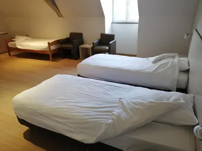 a room with three beds and a table and chairs at Het Rustpunt in Ghent