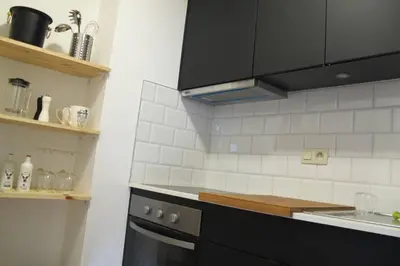 a kitchen with black cabinets and white tiles on the wall at Brussels Downtown in Brussels