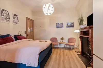 a bedroom with a bed and two chairs and a fireplace at Borgerhouse B&B in Antwerp