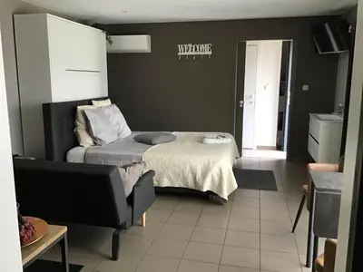 a bedroom with a bed and a chair in a room at Studio Gardenroom Guesthouse De Steenberg met wellness & tuinzicht in Geel