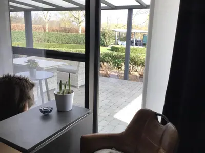 a view of a patio with a table and a chair at Studio Gardenroom Guesthouse De Steenberg met wellness & tuinzicht in Geel