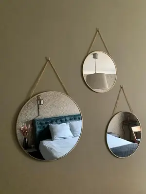 three mirrors hanging on a wall with a bed at B&B Vrijheid 4 in Arendonk