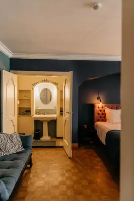 a bedroom with a bed and a couch and a mirror at B&B Vrijheid 4 in Arendonk