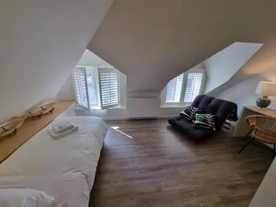 a bedroom with a bed and a couch and windows at De Kaai in Halle