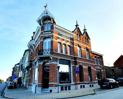 a red brick building with a tower on a street at De Kaai in Halle