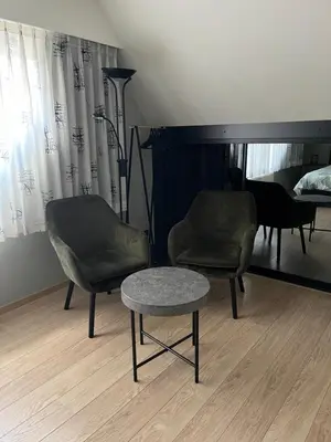 a room with two chairs and a table and a piano at Hazegewoud in Arendonk