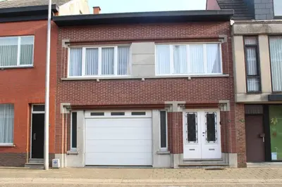 a red brick house with white garage doors at AmberHuis in Kasterlee