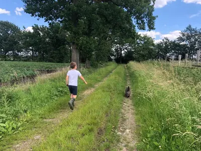 a boy and a cat walking down a dirt road at Op den Heust in Arendonk