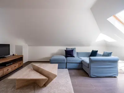 a living room with a blue couch and a tv at B&B Welness Sport and Pleasure in Laarne