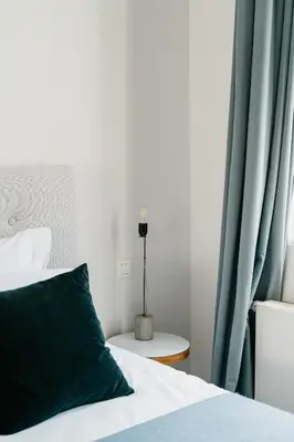 a bed with a green pillow next to a window at The 1880 Boutique Holiday Home in Antwerp
